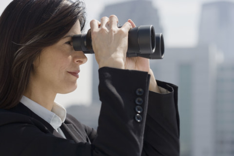Businesswoman looking through binoculars.