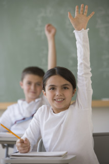 Girl raising hand in classroom.