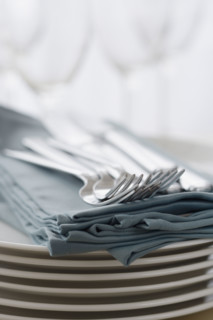 Stack of plates, silverware and napkins.
