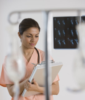 Indian female doctor writing on chart.