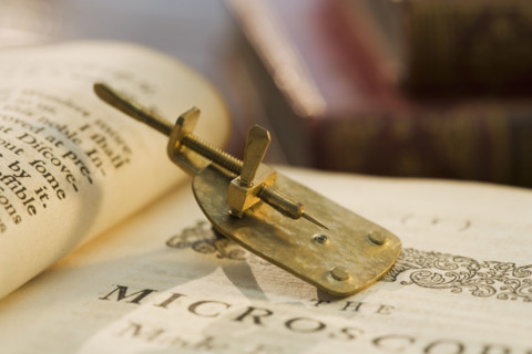 Model of Leeuwenhoek microscope on book.