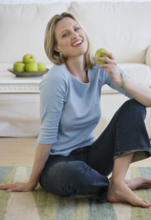 Woman holding apple on floor.