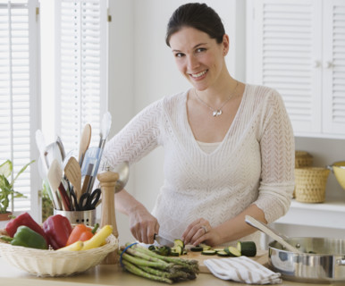 Woman chopping vegetables in kitchen.