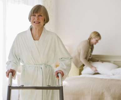 Senior woman using walker in bedroom.