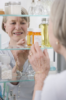 Senior woman looking in medicine cabinet.
