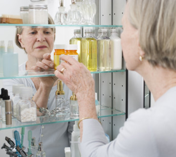 Senior woman looking in medicine cabinet.