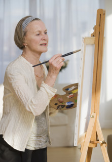 Senior woman painting on easel.