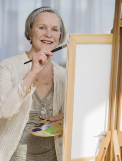 Senior woman painting on easel.