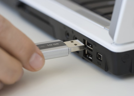 Man plugging USB stick into laptop.