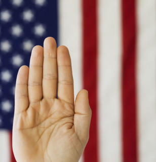 Man’s hand up in front of American flag.