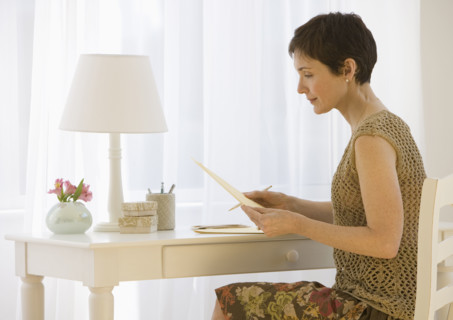 Woman writing letter at desk.
