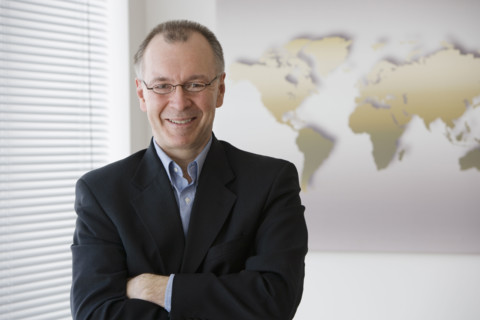 Businessman with arms crossed in front of map.