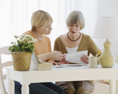 Mother and adult daughter looking at bills.