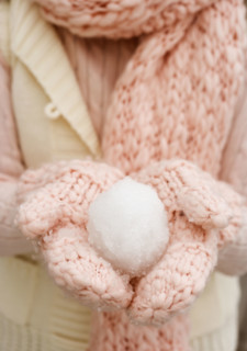 Person holding snowball in gloved hands.