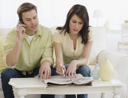 Couple reading classifieds in newspaper.