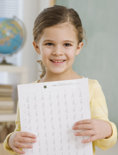 Portrait of girl holding paper in school.
