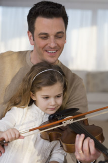 Father helping daughter play violin.
