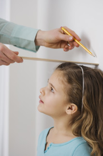 Mother marking daughter’s height on wall.