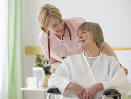 Nurse pushing senior woman in wheelchair.