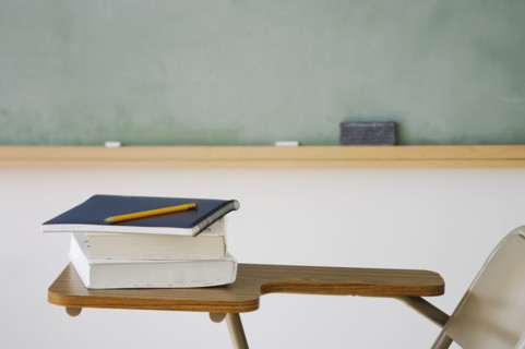 Books and pencil on desk in classroom.