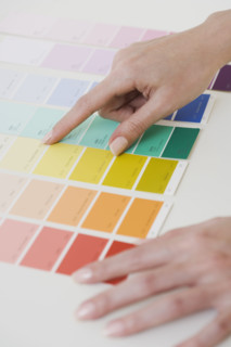 Close up of woman comparing paint swatches.
