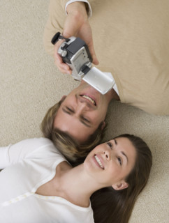 Couple video recording themselves on floor.