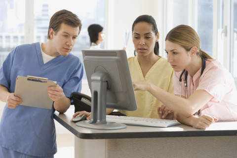 Doctors looking at computer in hospital.
