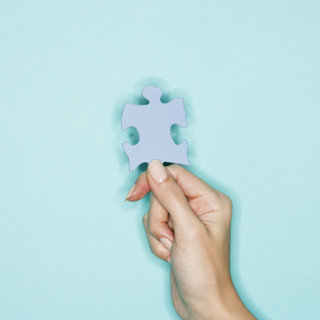 Woman holding jigsaw puzzle piece.