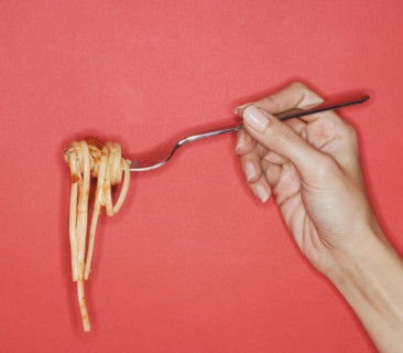 Woman holding forkful of pasta.