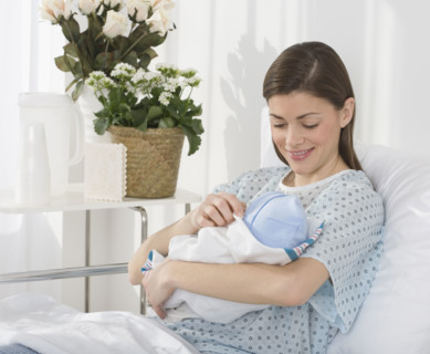 Mother smiling at newborn baby in hospital.