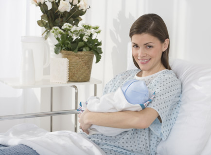 Portrait of mother holding newborn baby in hospital.