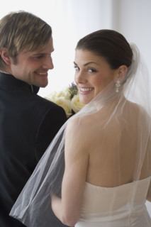 Portrait of bride and groom looking over shoulders.