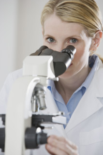 Female scientist looking into microscope.