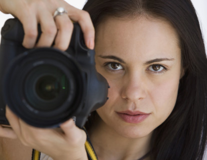 Woman holding camera next to face.