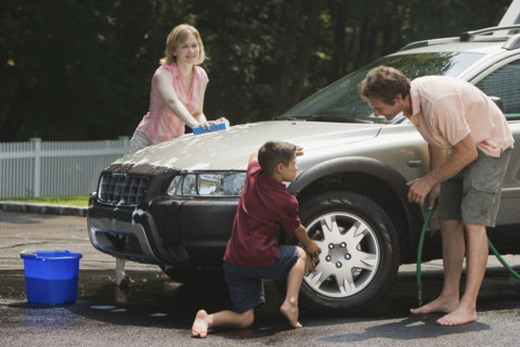 Family washing car in driveway.