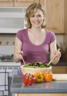 Woman tossing salad in kitchen.
