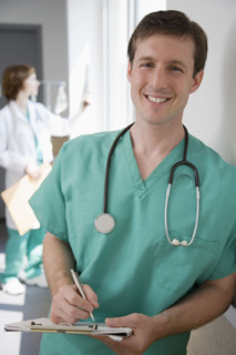 Male doctor writing on chart.