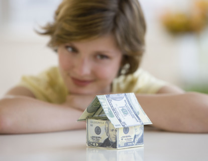 Woman looking at model house made of US dollars.