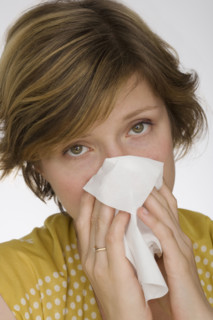 Close up of woman blowing nose.
