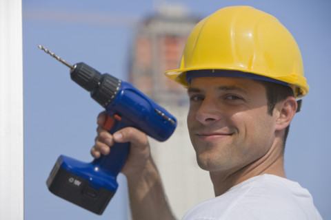 Construction worker holding cordless drill.