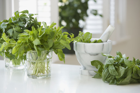 Fresh herbs next to mortar and pestle.