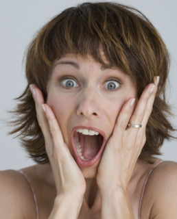 Woman looking surprised with hands on cheeks.