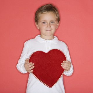 Boy holding heart-shaped box.