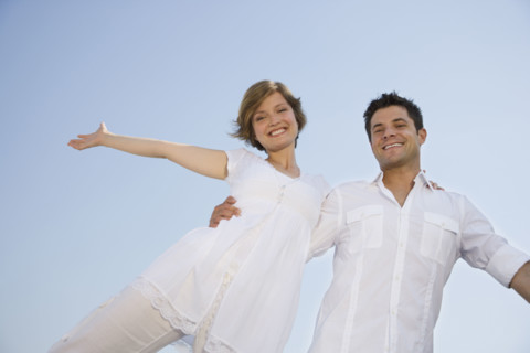 Low angle view of couple with arms outstretched.