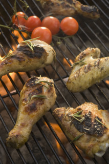 Chicken pieces cooking on grill.