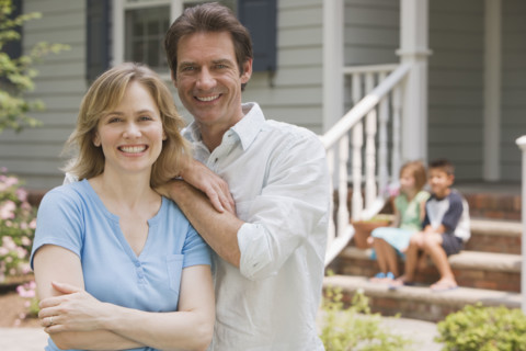 Couple hugging with children in background.