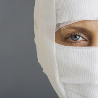 Woman’s face wrapped in bandages.