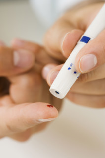 Person using blood sugar monitor on finger.