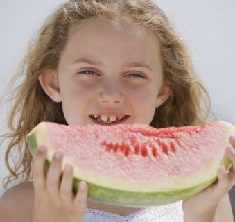 Girl eating slice of watermelon.