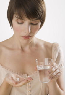 Woman taking pills with glass of water.